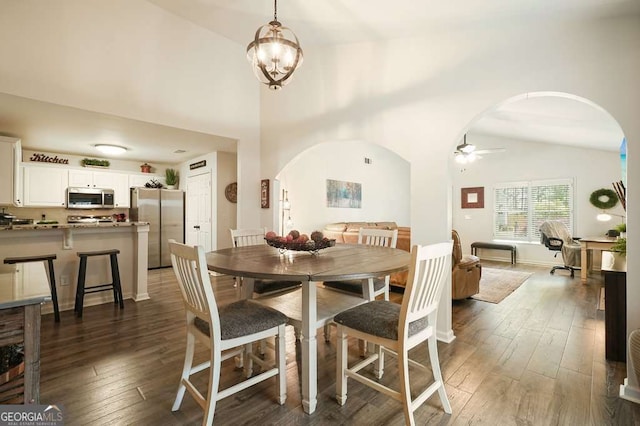 dining space with ceiling fan with notable chandelier, vaulted ceiling, arched walkways, and wood-type flooring