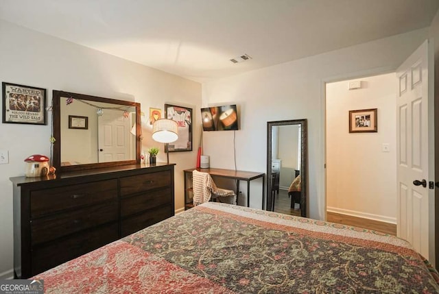 bedroom featuring baseboards, wood finished floors, and visible vents