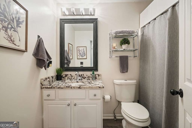 bathroom with toilet, vanity, and baseboards