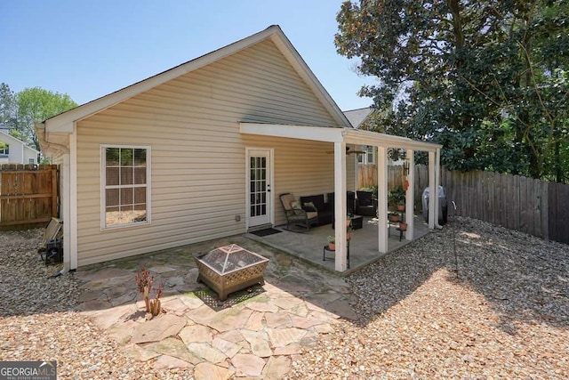 rear view of property with a fenced backyard, a patio, and an outdoor fire pit