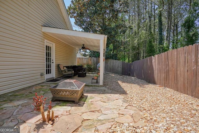 view of patio / terrace featuring a fenced backyard, a ceiling fan, and an outdoor living space with a fire pit