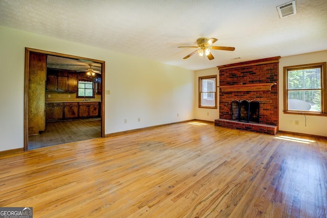 unfurnished living room featuring ceiling fan, baseboards, wood finished floors, and visible vents
