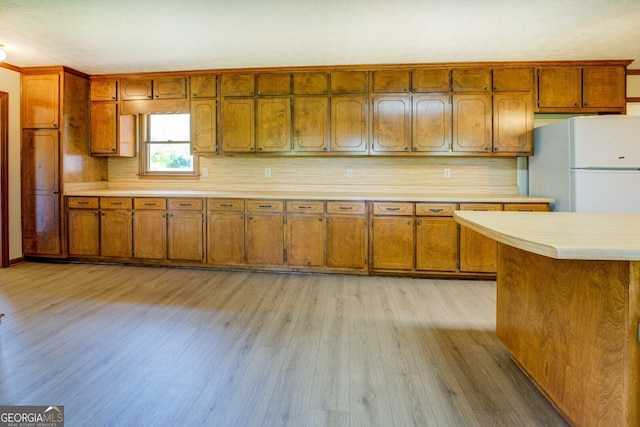 kitchen featuring brown cabinets, freestanding refrigerator, and light countertops