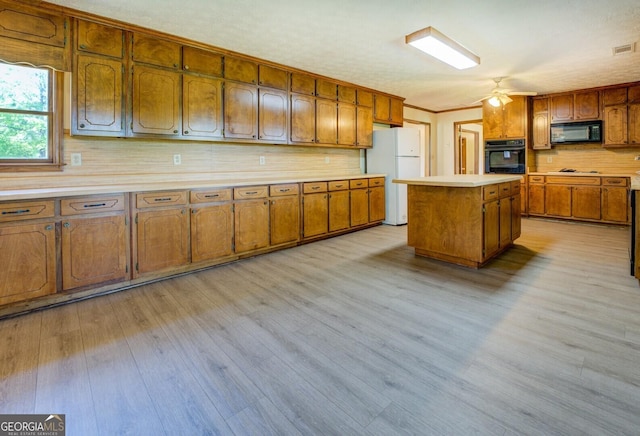 kitchen with light wood-type flooring, light countertops, brown cabinets, and black appliances