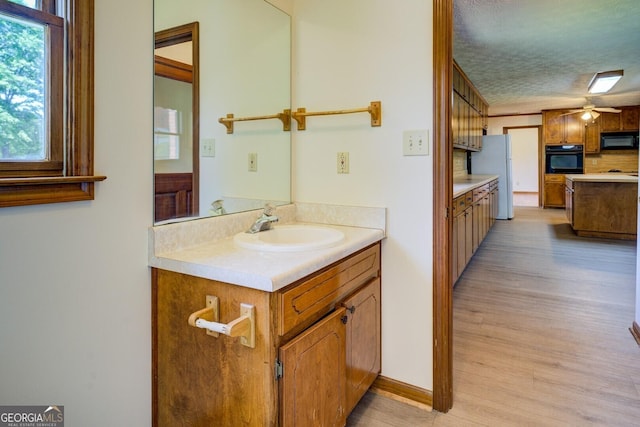 bathroom featuring a ceiling fan, vanity, wood finished floors, and a textured ceiling