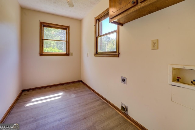clothes washing area with electric dryer hookup, cabinet space, washer hookup, and a wealth of natural light