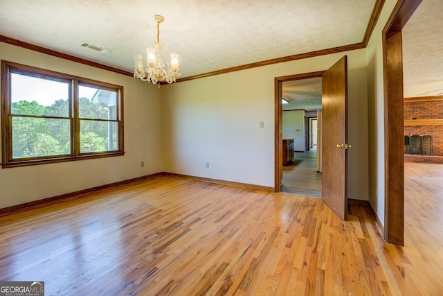unfurnished room featuring a textured ceiling, light wood-type flooring, visible vents, a notable chandelier, and crown molding