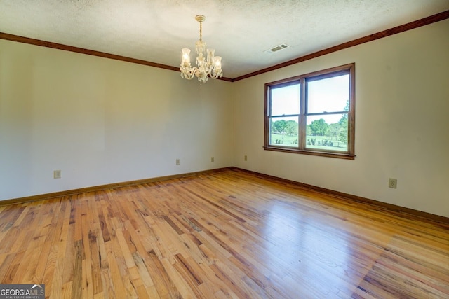 unfurnished room featuring crown molding, a chandelier, light wood-style flooring, baseboards, and visible vents