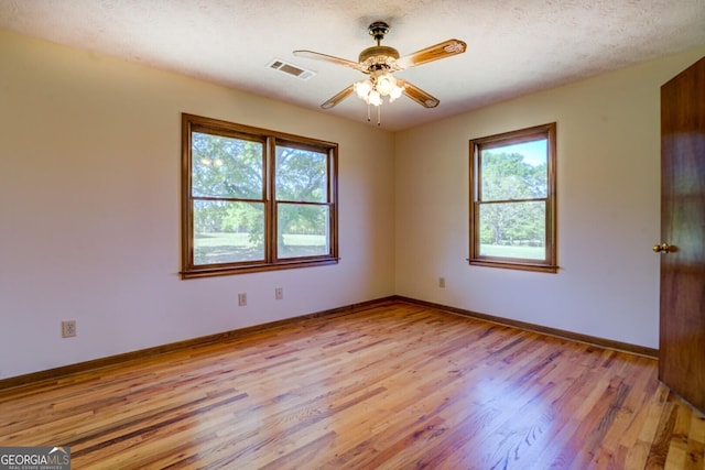 unfurnished room with light wood-type flooring, baseboards, a ceiling fan, and visible vents