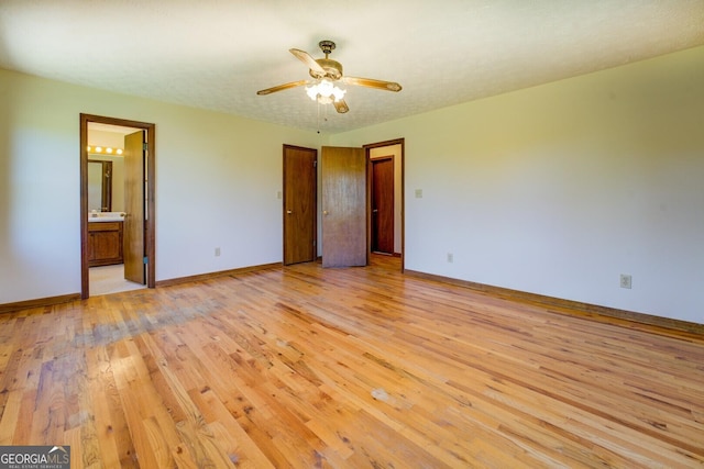 unfurnished bedroom featuring light wood-style flooring, baseboards, connected bathroom, and a sink