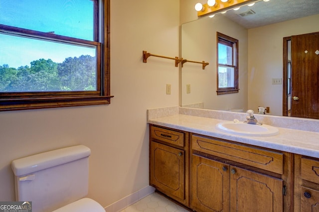 bathroom with baseboards, visible vents, vanity, and toilet