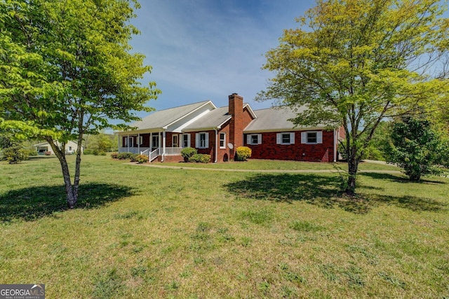 view of front of house with brick siding, a front yard, and covered porch