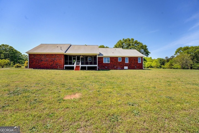 rear view of house featuring a yard and a sunroom
