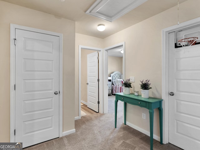 hall with carpet flooring, baseboards, and attic access