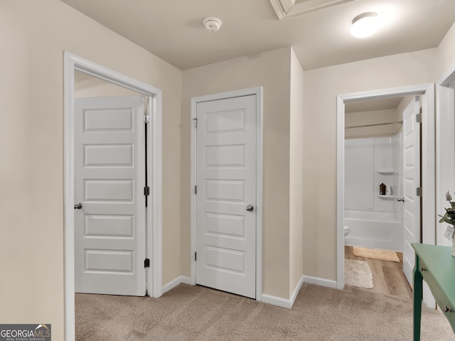 hallway with light colored carpet and baseboards