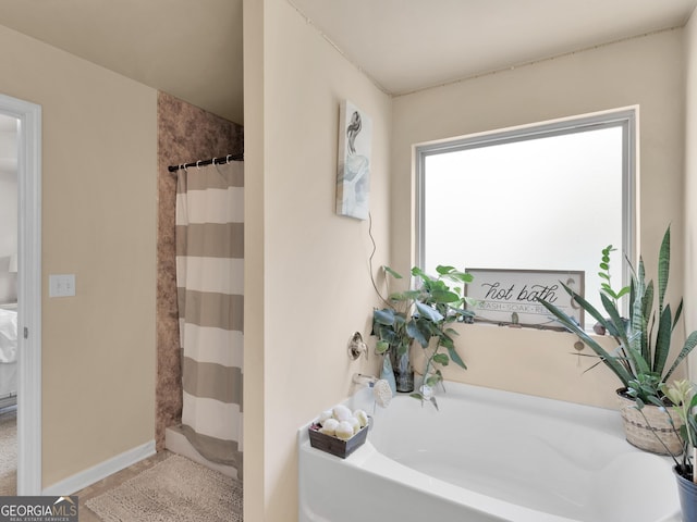 full bath with a garden tub, curtained shower, and baseboards