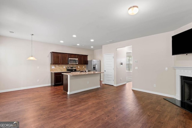 kitchen with appliances with stainless steel finishes, open floor plan, an island with sink, decorative backsplash, and recessed lighting