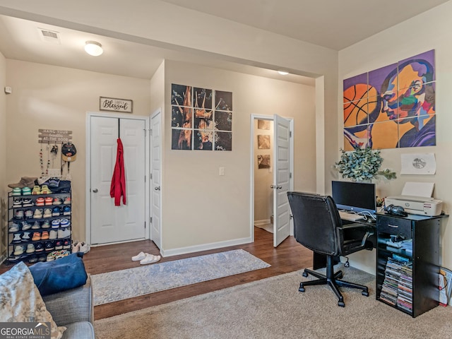carpeted office space with wood finished floors and baseboards