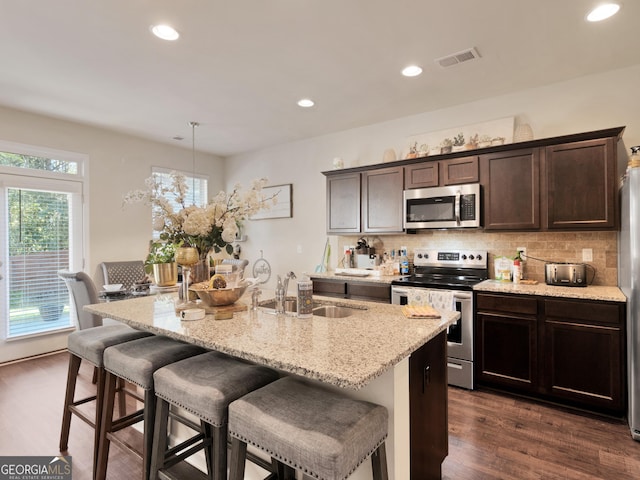 kitchen featuring stainless steel appliances, a sink, tasteful backsplash, dark wood-type flooring, and recessed lighting