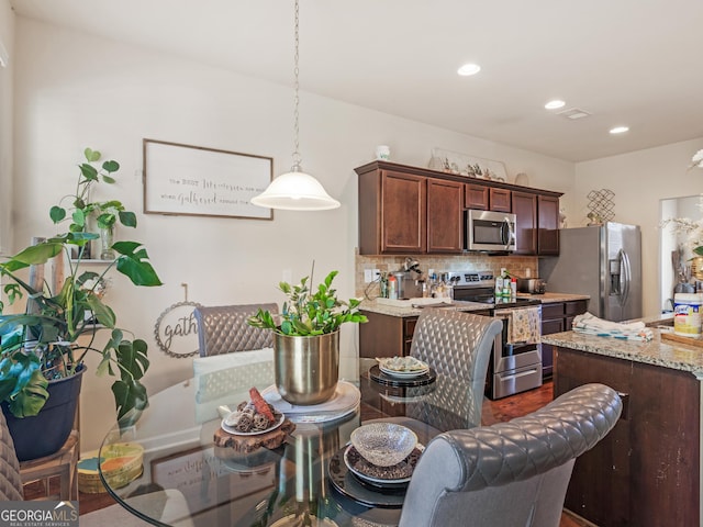 kitchen with stainless steel appliances, decorative backsplash, recessed lighting, hanging light fixtures, and light stone countertops