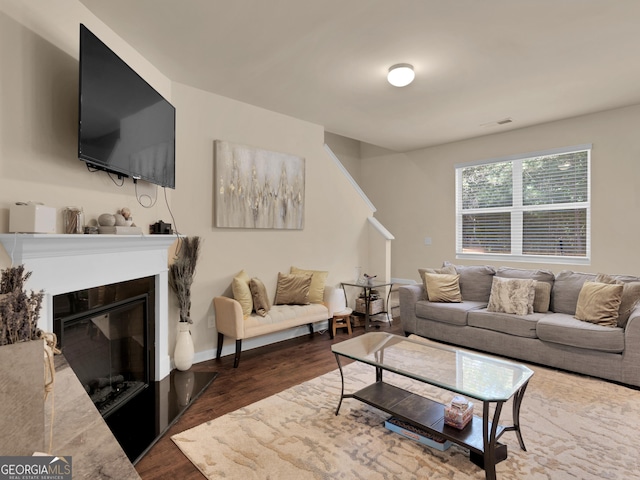 living room featuring dark wood finished floors, a glass covered fireplace, and baseboards