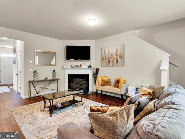 living area with wood finished floors, a glass covered fireplace, baseboards, and stairway