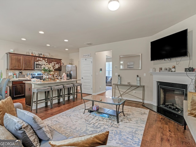 living room with wood finished floors, a glass covered fireplace, and recessed lighting