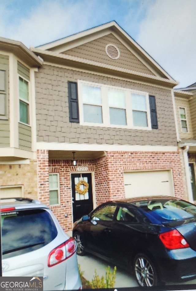 multi unit property featuring brick siding and an attached garage