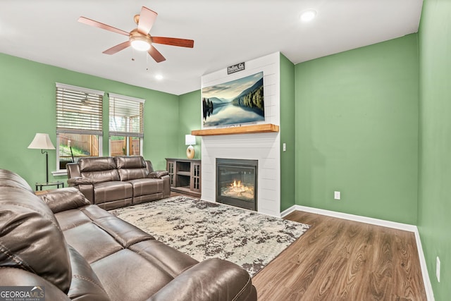 living room featuring recessed lighting, wood finished floors, a ceiling fan, baseboards, and a large fireplace