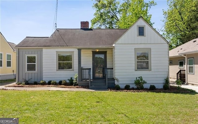 bungalow-style house featuring board and batten siding, a front yard, and a chimney