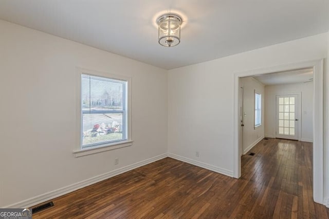 unfurnished room featuring healthy amount of natural light, dark wood-style flooring, and baseboards