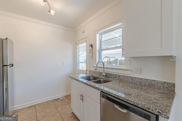 kitchen with stainless steel appliances, a sink, light stone countertops, white cabinets, and crown molding