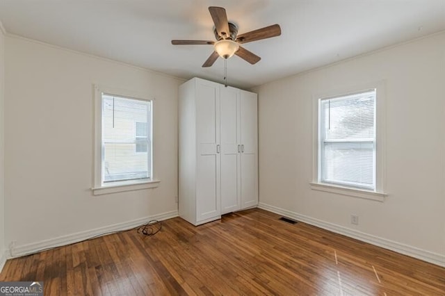 unfurnished bedroom with wood-type flooring, crown molding, baseboards, and ceiling fan