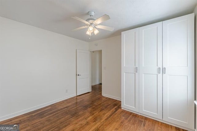 unfurnished bedroom with wood finished floors, baseboards, and ceiling fan