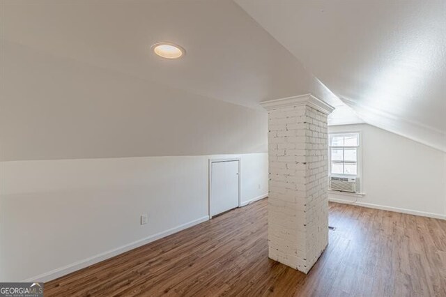 additional living space featuring lofted ceiling, wood finished floors, baseboards, and decorative columns