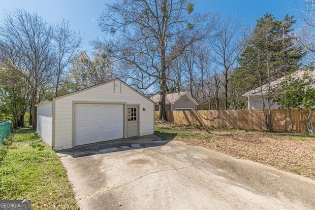 detached garage with fence and concrete driveway