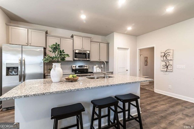 kitchen with stainless steel appliances, a kitchen breakfast bar, a sink, and gray cabinets