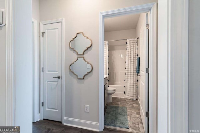 bathroom with baseboards, toilet, and shower / bathtub combination with curtain