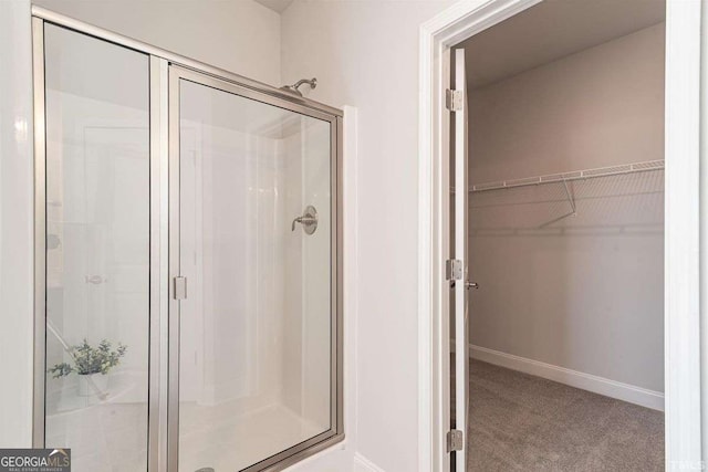 bathroom featuring baseboards, a shower stall, and a walk in closet
