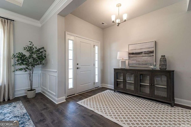 foyer entrance with wood finished floors, visible vents, crown molding, baseboards, and a chandelier