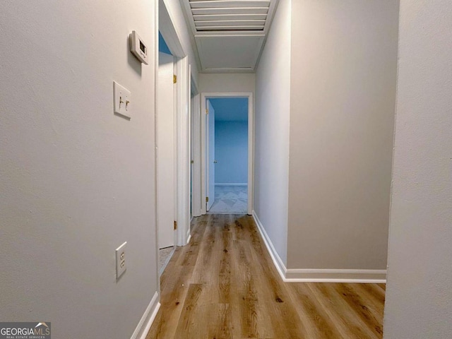 corridor featuring light wood-style flooring and baseboards