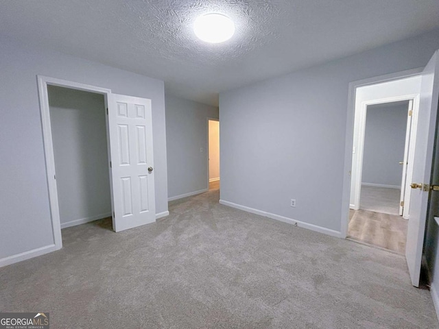 unfurnished bedroom featuring carpet floors, a textured ceiling, and baseboards