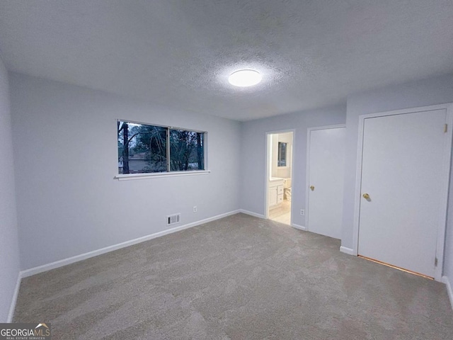 carpeted empty room with a textured ceiling, visible vents, and baseboards