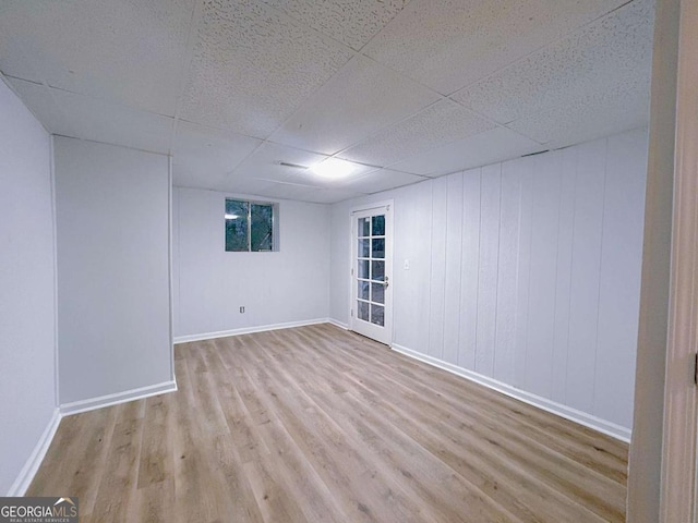 below grade area featuring baseboards, a paneled ceiling, and wood finished floors