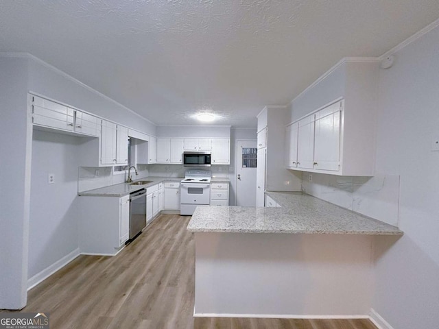 kitchen with stainless steel appliances, ornamental molding, light stone countertops, a peninsula, and light wood-style flooring