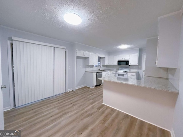 kitchen with light wood finished floors, a peninsula, a textured ceiling, appliances with stainless steel finishes, and white cabinetry