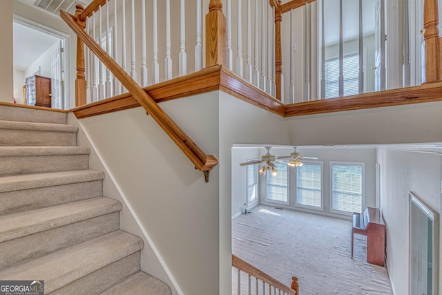 stairs with carpet flooring and ceiling fan