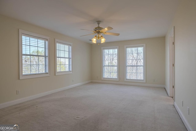 spare room featuring baseboards, light colored carpet, and ceiling fan