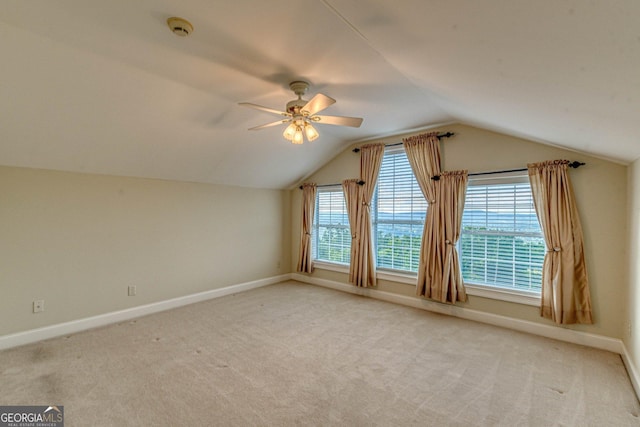 additional living space featuring baseboards, vaulted ceiling, a ceiling fan, and light colored carpet