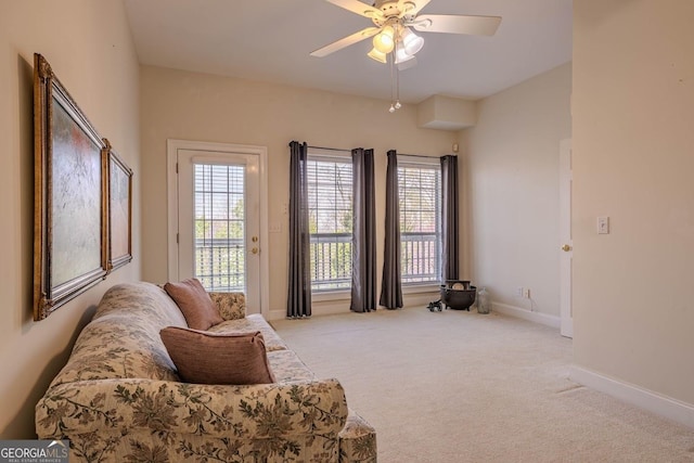 living area with baseboards, a ceiling fan, and carpet flooring